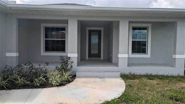 14464 Fort Myers Ave, Port Charlotte, FL 33981 - doorway to property featuring stucco siding and a porch