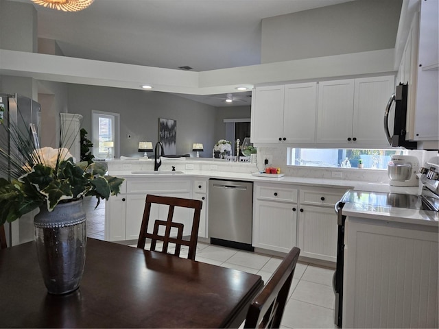 kitchen featuring white cabinets, sink, light tile patterned flooring, kitchen peninsula, and stainless steel appliances