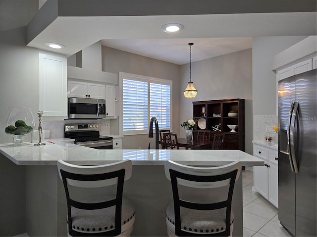 kitchen featuring white cabinetry, kitchen peninsula, a breakfast bar area, and appliances with stainless steel finishes