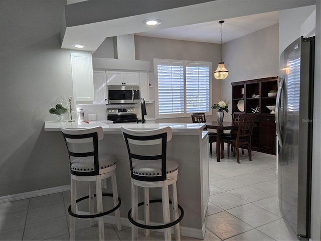 kitchen with white cabinets, a kitchen bar, kitchen peninsula, and appliances with stainless steel finishes