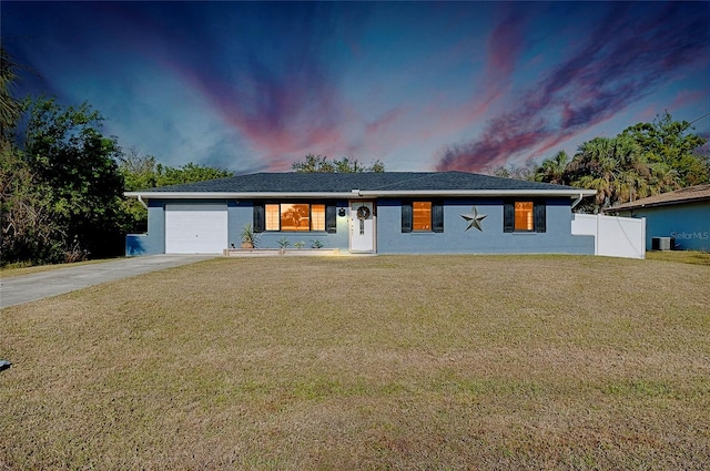 single story home with central AC, a garage, and a lawn