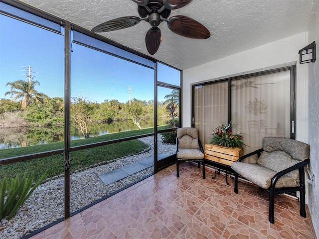 sunroom / solarium featuring ceiling fan, plenty of natural light, and a water view