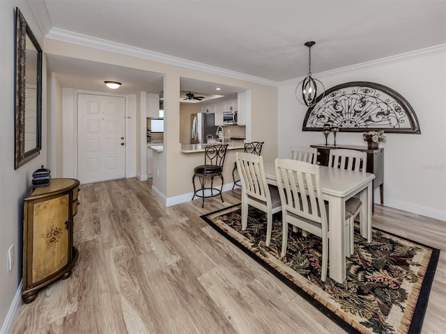 dining space with ceiling fan with notable chandelier, light hardwood / wood-style flooring, and ornamental molding