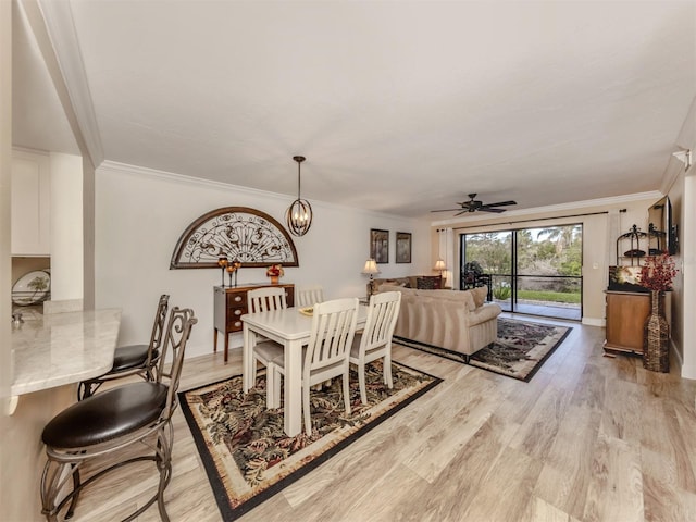 dining space featuring crown molding, ceiling fan with notable chandelier, and light wood-type flooring