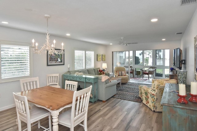 dining space with ceiling fan with notable chandelier and light hardwood / wood-style floors