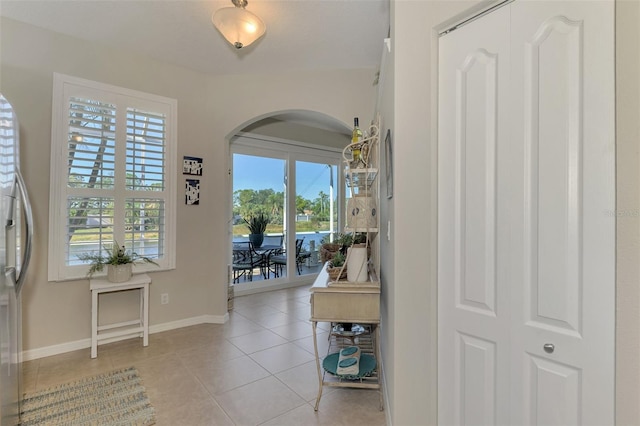 entrance foyer with light tile patterned floors, arched walkways, and baseboards