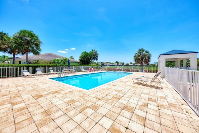 community pool featuring fence and a patio