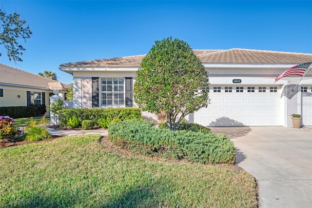 ranch-style home with driveway, a front lawn, an attached garage, and stucco siding