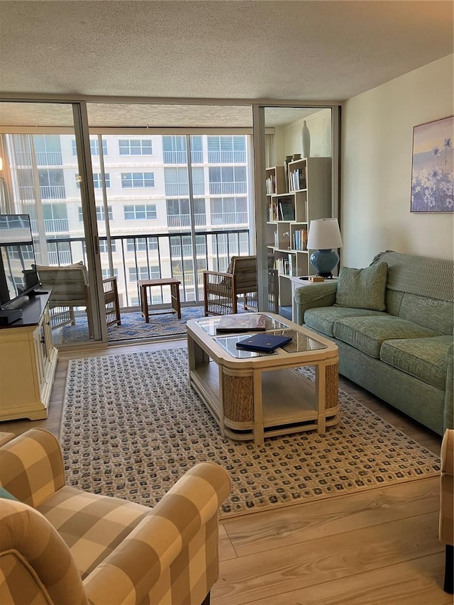 living room featuring a wall of windows, a textured ceiling, and light wood-type flooring