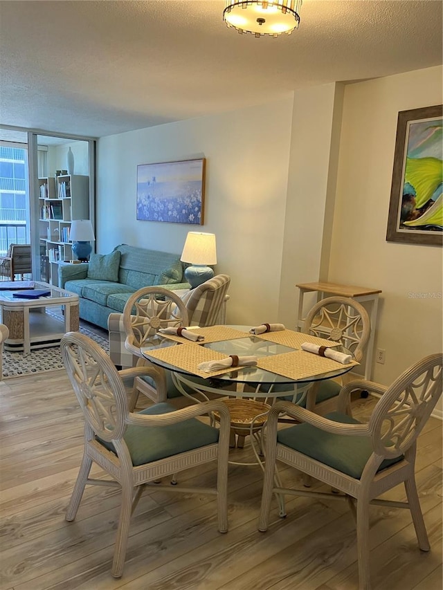 dining space with light hardwood / wood-style floors, a wall of windows, and a textured ceiling