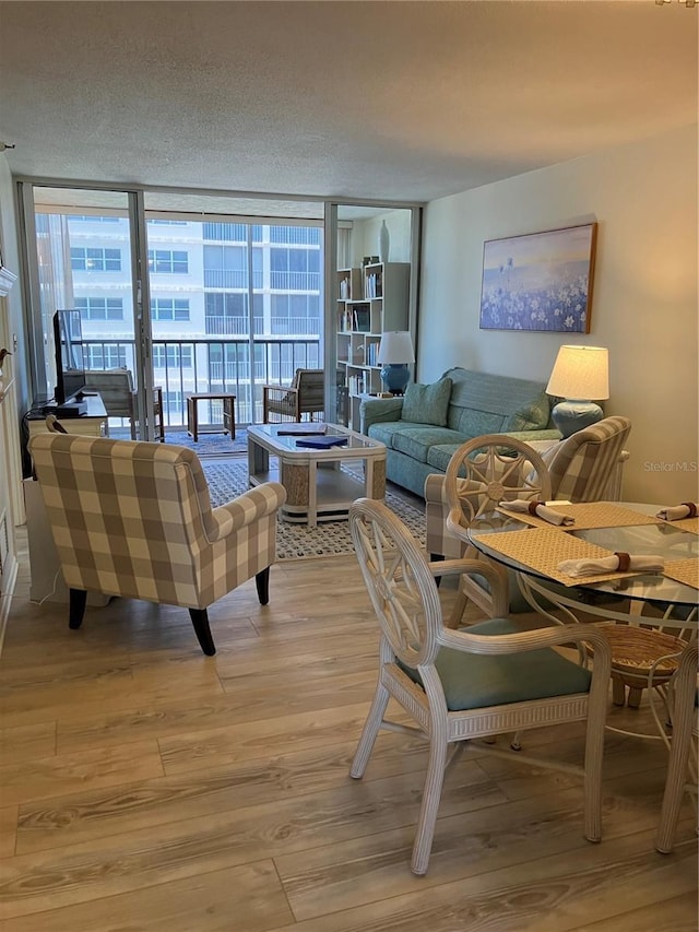 living room featuring a wall of windows, a textured ceiling, and light hardwood / wood-style flooring