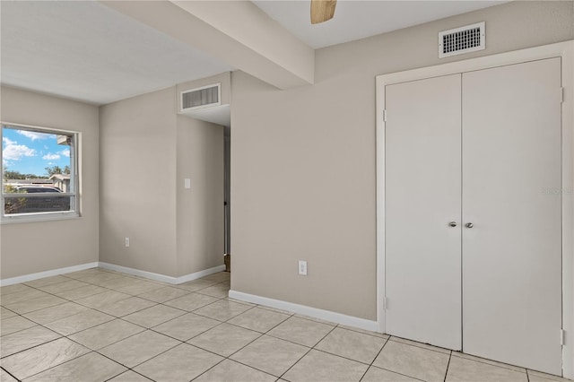 unfurnished bedroom with ceiling fan, light tile patterned floors, and a closet