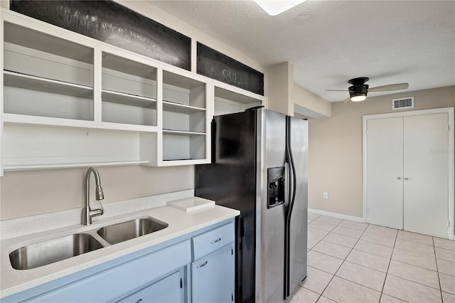 kitchen featuring ceiling fan, sink, stainless steel fridge, a textured ceiling, and light tile patterned flooring