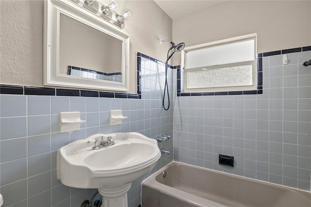 bathroom featuring tiled shower / bath, tile walls, and sink