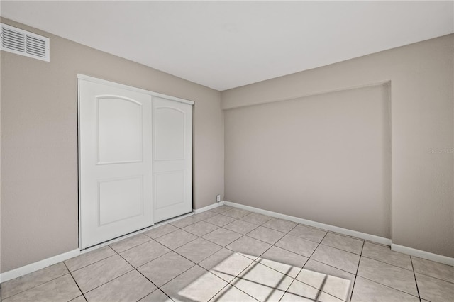 unfurnished bedroom with light tile patterned floors and a closet