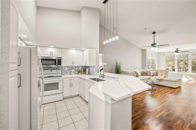 kitchen featuring kitchen peninsula, white appliances, white cabinetry, and sink