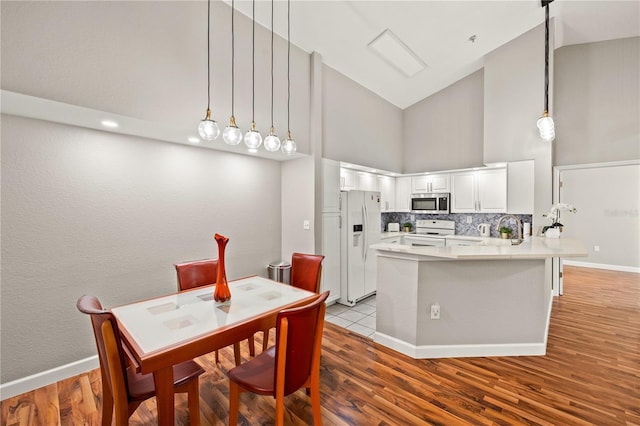 dining room featuring a high ceiling, light wood-type flooring, and sink