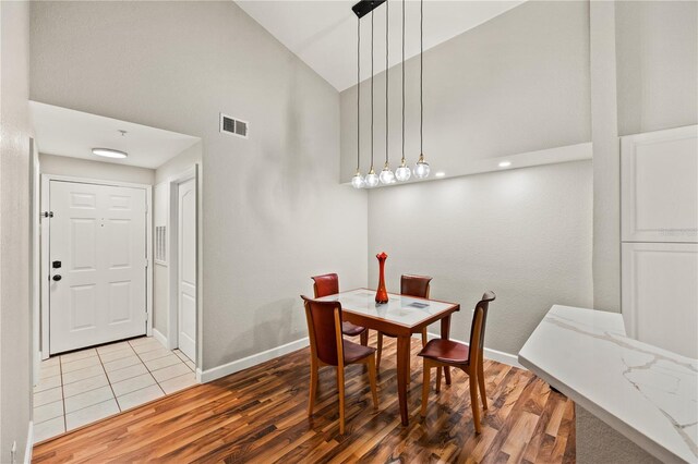 dining room featuring high vaulted ceiling and light hardwood / wood-style flooring