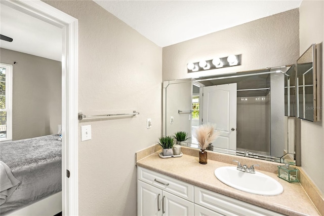 bathroom with a tile shower, vanity, and a healthy amount of sunlight