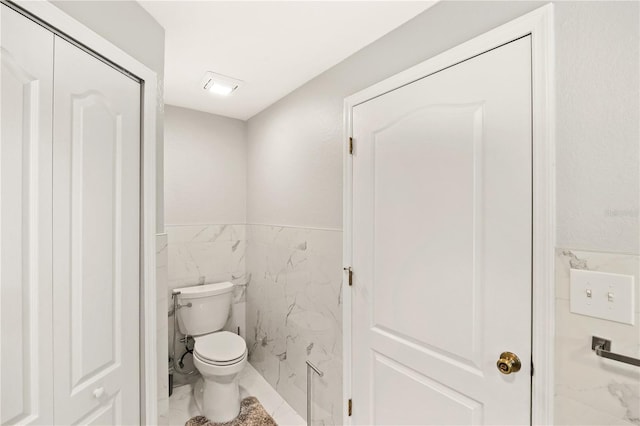 bathroom with toilet and tile walls