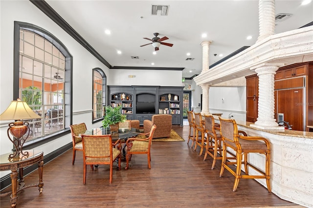 dining room featuring ceiling fan, crown molding, ornate columns, and dark wood-type flooring