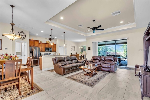 tiled living room featuring ceiling fan, ornamental molding, and a tray ceiling