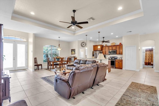 living room featuring ceiling fan, french doors, light tile patterned floors, a tray ceiling, and ornamental molding