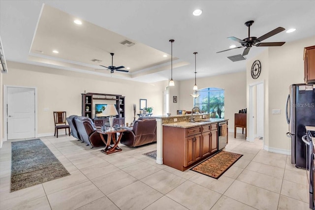 kitchen with light stone counters, hanging light fixtures, a raised ceiling, and stainless steel appliances