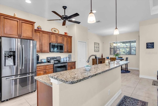 kitchen with an island with sink, light stone counters, and appliances with stainless steel finishes