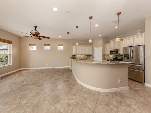 kitchen with pendant lighting, tasteful backsplash, ceiling fan, stainless steel appliances, and light stone countertops