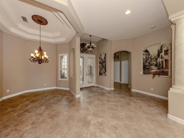 entrance foyer with an inviting chandelier, a raised ceiling, and ornate columns