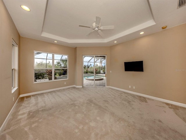 unfurnished living room featuring plenty of natural light, a tray ceiling, and light carpet