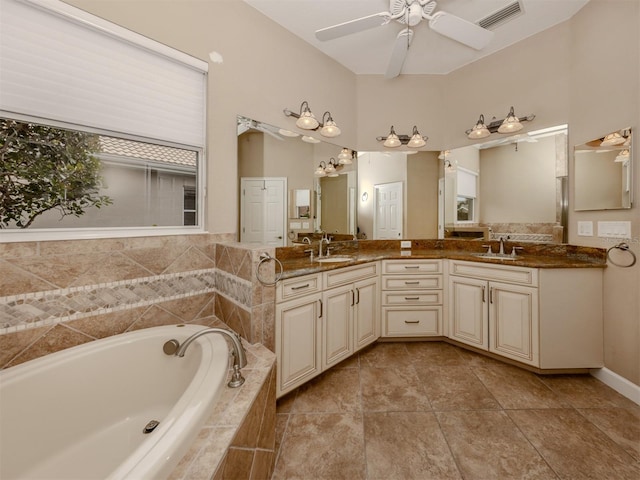 bathroom with tiled tub, vanity, and ceiling fan