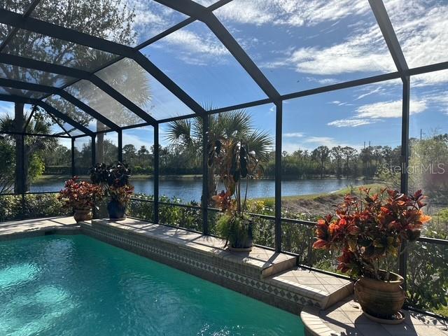 view of pool with a water view, a lanai, and a patio area