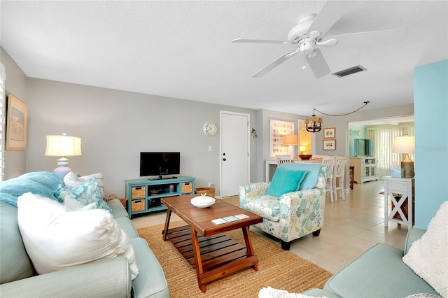 tiled living room featuring ceiling fan with notable chandelier