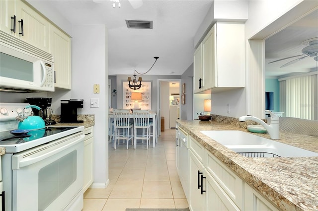 kitchen featuring ceiling fan with notable chandelier, light tile patterned floors, white appliances, and sink