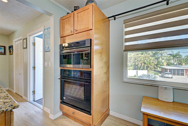 kitchen with light hardwood / wood-style flooring, built in desk, a textured ceiling, and multiple ovens