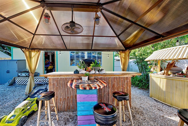 deck with a gazebo, ceiling fan, and a bar