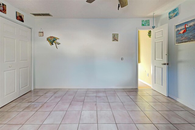 tiled spare room featuring ceiling fan