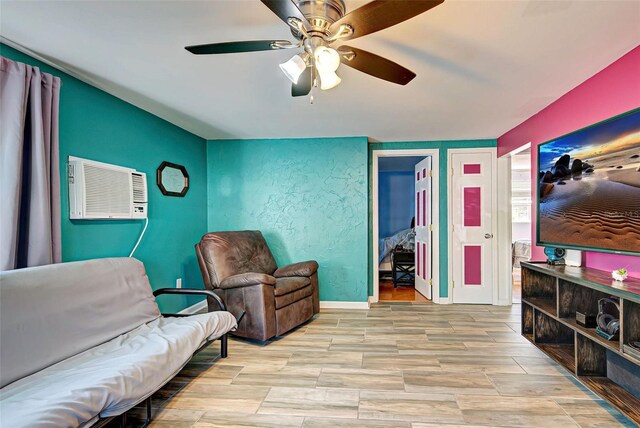 sitting room with ceiling fan and an AC wall unit