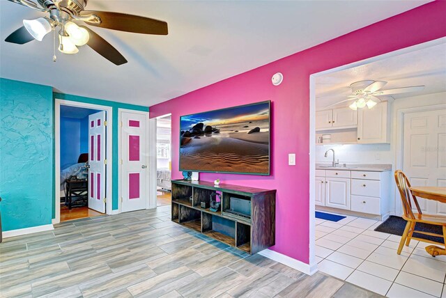 living room featuring ceiling fan, sink, and light hardwood / wood-style flooring