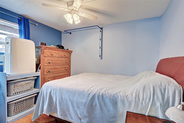 bedroom with ceiling fan, wood-type flooring, and a textured ceiling