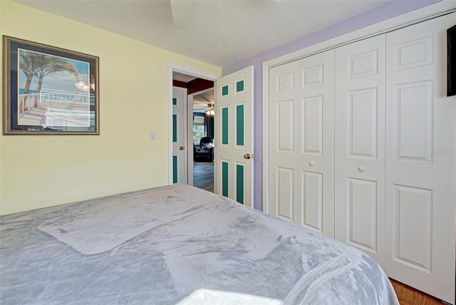 bedroom with a textured ceiling, dark hardwood / wood-style floors, a closet, and ceiling fan