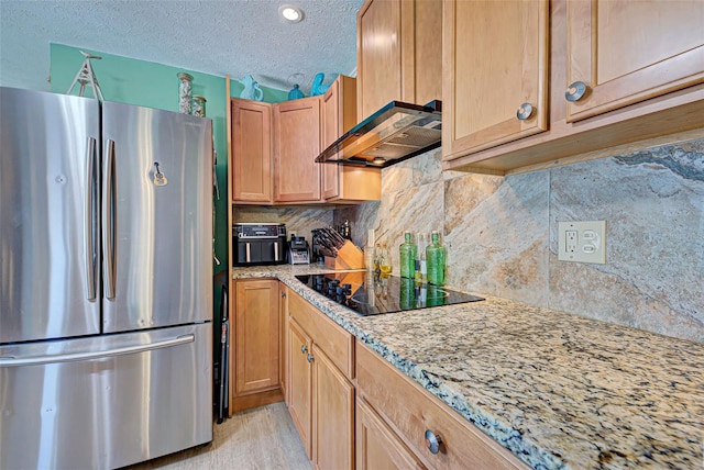 kitchen with custom exhaust hood, black electric cooktop, a textured ceiling, light stone counters, and stainless steel refrigerator