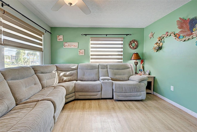 living room featuring plenty of natural light, ceiling fan, a textured ceiling, and light hardwood / wood-style flooring