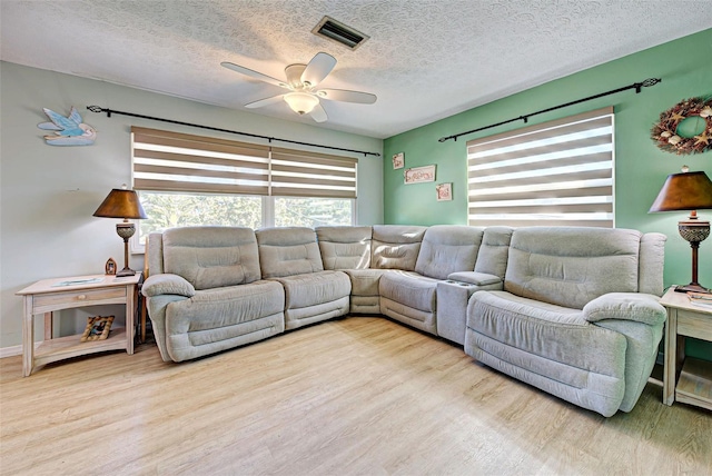 living room with ceiling fan, light hardwood / wood-style flooring, and a textured ceiling