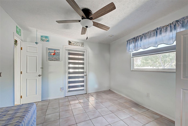 unfurnished bedroom featuring light tile patterned floors, a textured ceiling, and ceiling fan