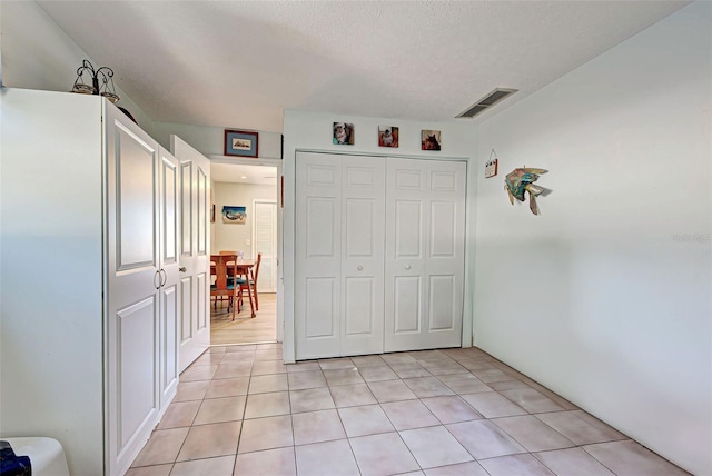 unfurnished bedroom with light tile patterned floors, a textured ceiling, and a closet