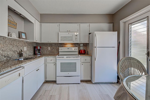 kitchen with white appliances, white cabinets, sink, light stone countertops, and tasteful backsplash