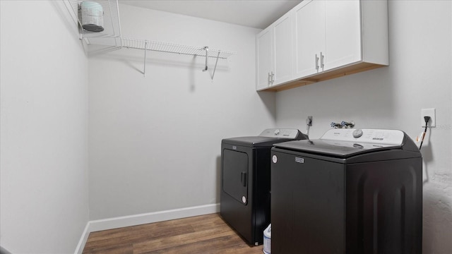 washroom featuring washer and dryer, dark hardwood / wood-style floors, and cabinets